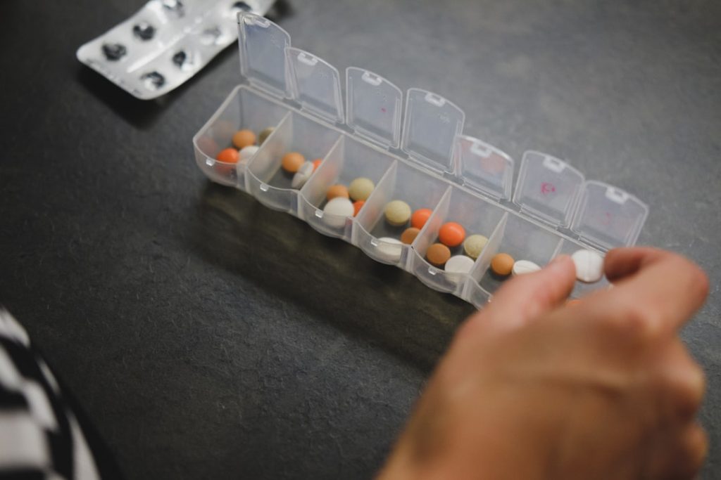 person-about-to-pick-medicine-from-medicine-organizer-1tl8aoedj-c